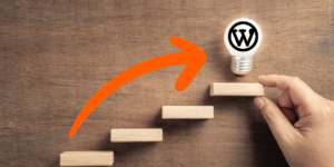 Escalier avec ampoule et logo Wordpress en haut tenue par un main